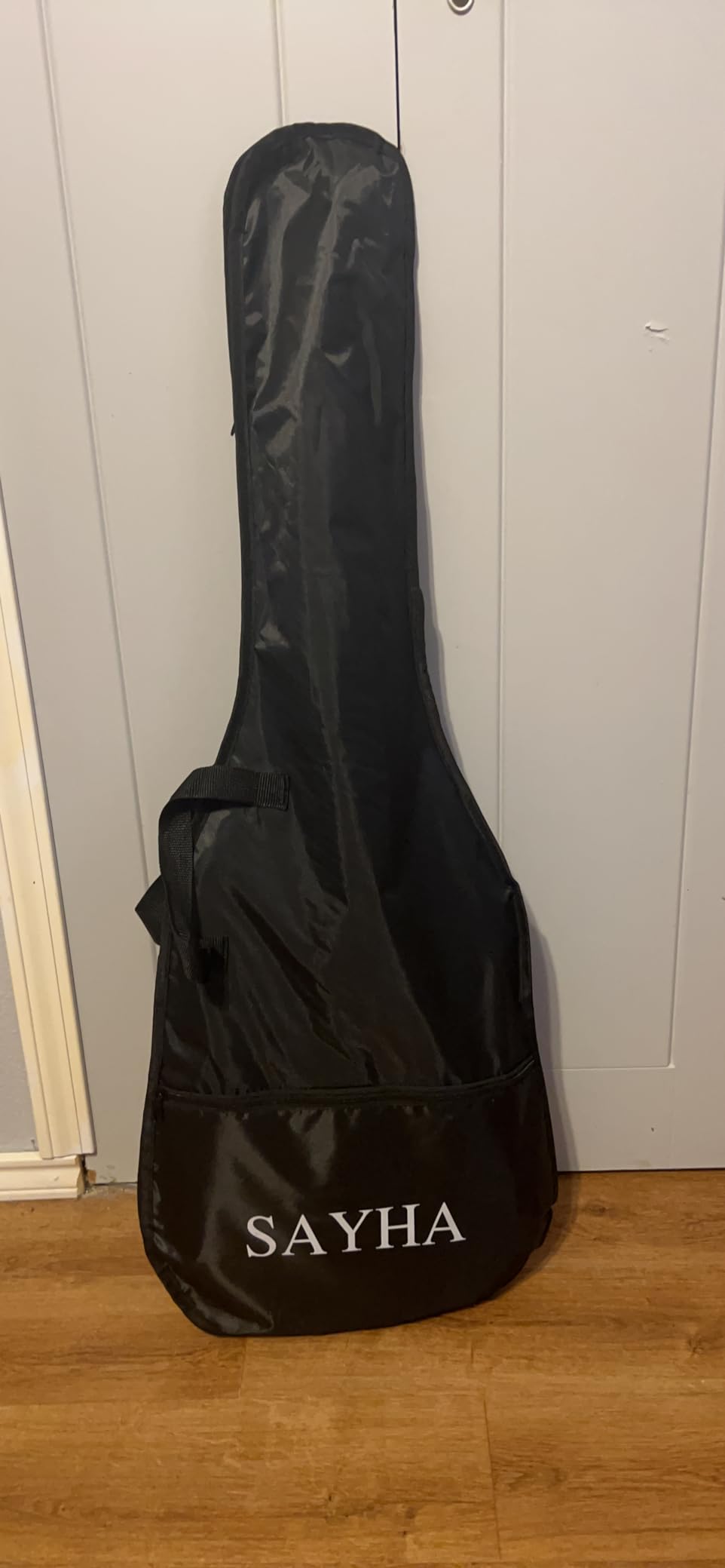 Black Sayha gig bag with the Sayha logo on the front pocket, leaning against a door